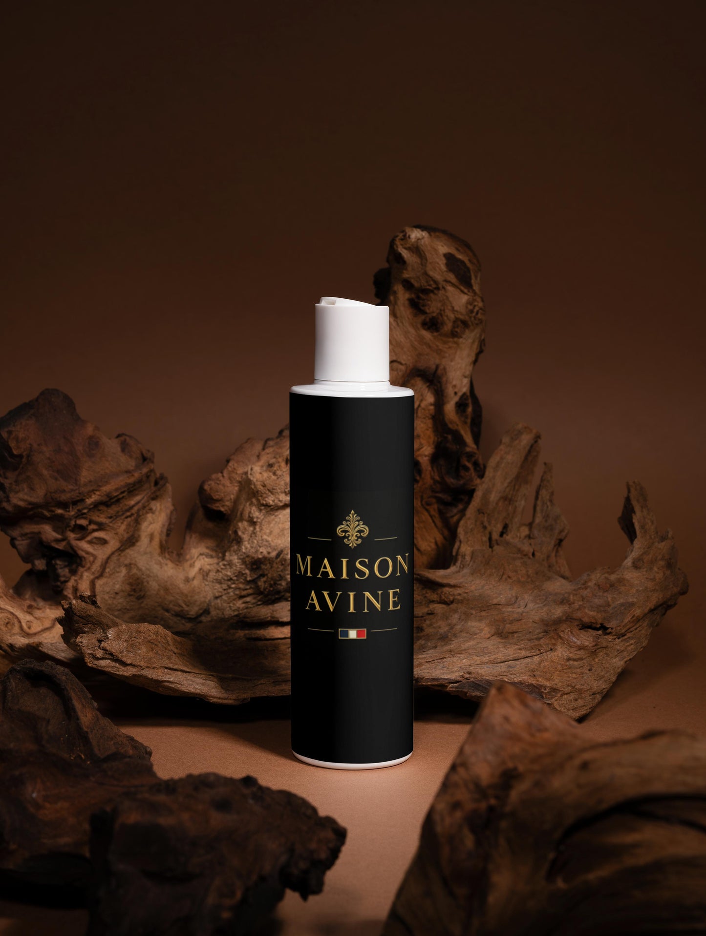 Black cylindrical bottle with white cap labeled 'Maison Avine' on a brown background with wooden elements.