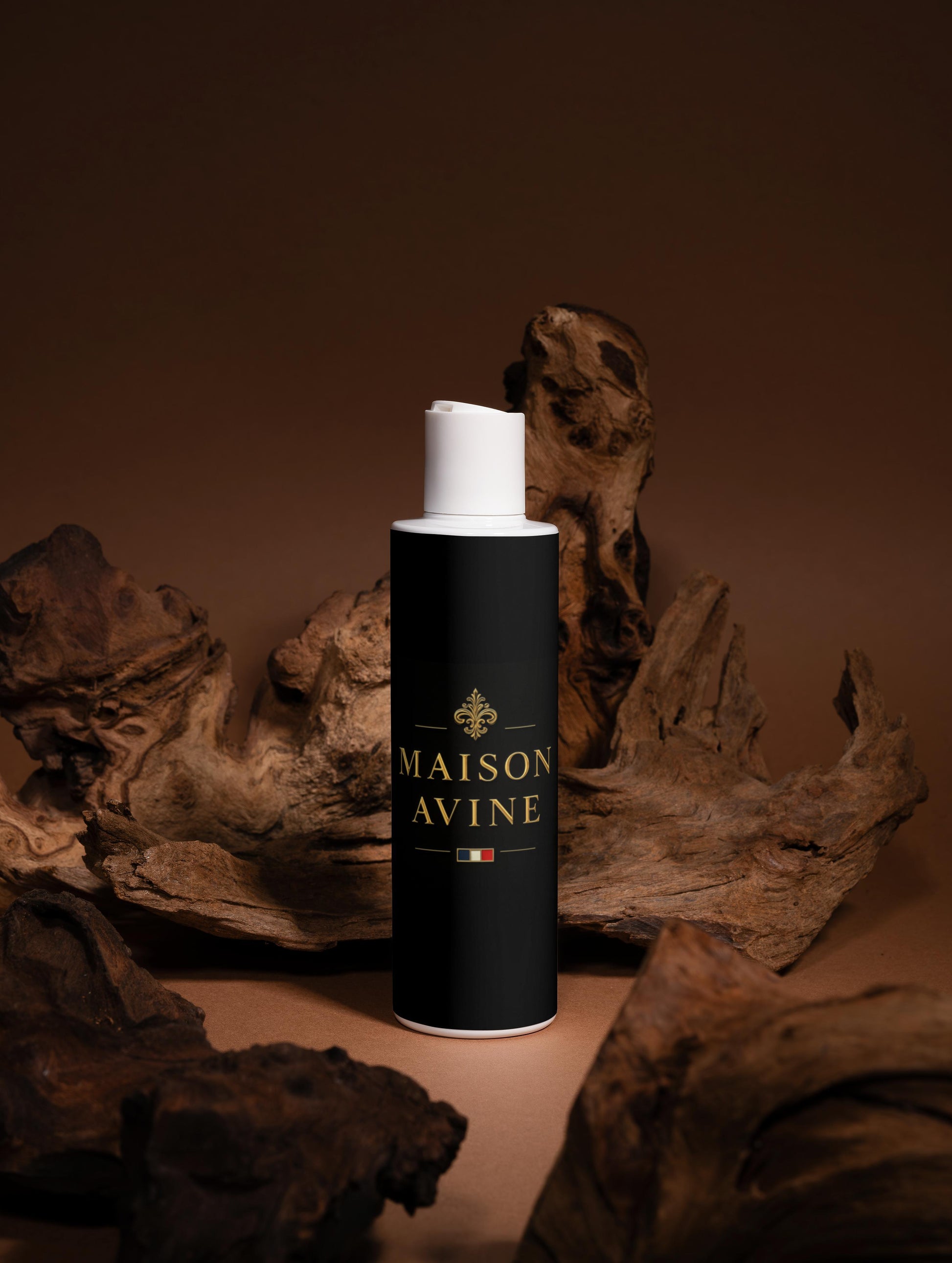 Black cylindrical bottle with white cap labeled 'Maison Avine' on a brown background with wooden elements.