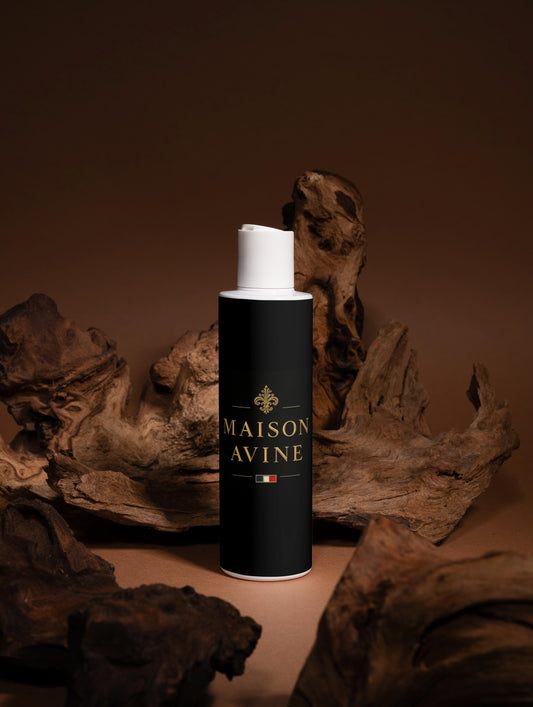 Black cylindrical bottle with white cap labeled 'Maison Avine' on a brown background with wooden elements.